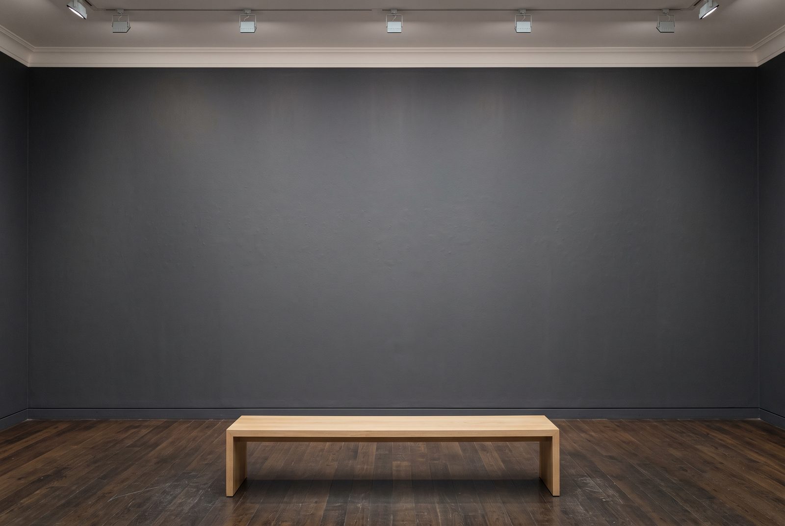 Visuel d'ambiance : une longue salle de musée voûtée, murs de pierre claire et œuvres espacées sous un éclairage rasant