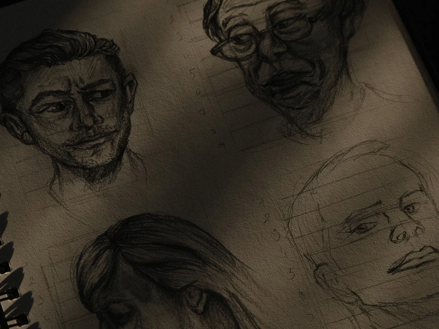 Une page de carnet couverte d'études de visages au crayon, dans une lumière rasante